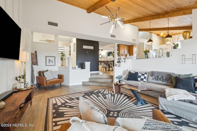 living room with beam ceiling, an inviting chandelier, a towering ceiling, wood-type flooring, and wood ceiling