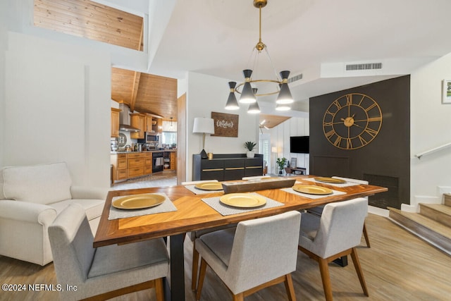 dining area with high vaulted ceiling, light hardwood / wood-style floors, and an inviting chandelier