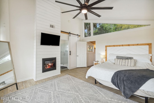 bedroom with ceiling fan, a fireplace, high vaulted ceiling, and light hardwood / wood-style flooring