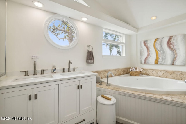 bathroom featuring a washtub, vanity, and lofted ceiling