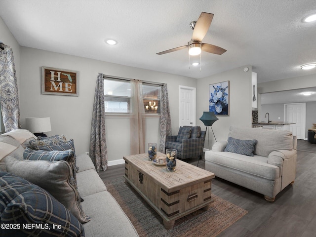 living room featuring dark hardwood / wood-style floors, ceiling fan, sink, and a textured ceiling