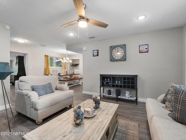 living room with ceiling fan with notable chandelier, a textured ceiling, and dark wood-type flooring