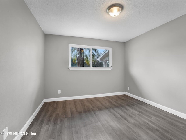 empty room with a textured ceiling and dark hardwood / wood-style floors