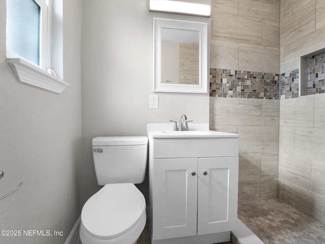 bathroom with vanity, toilet, and tiled shower