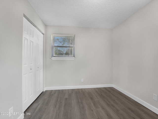 unfurnished bedroom with a textured ceiling, dark hardwood / wood-style flooring, and a closet