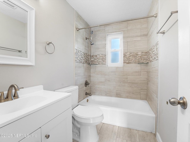 full bathroom featuring tiled shower / bath, vanity, and toilet