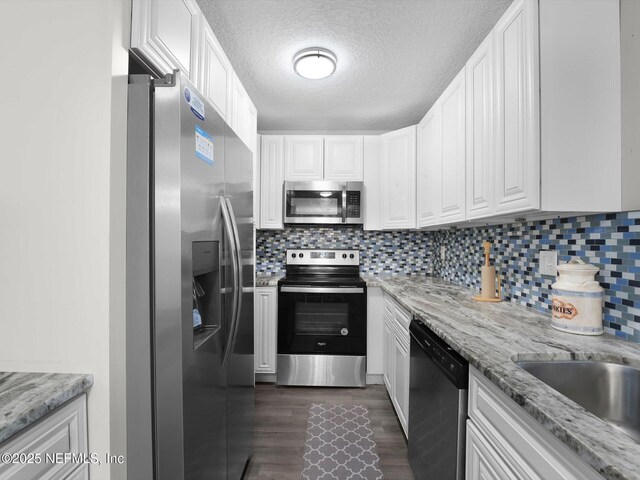 kitchen with white cabinets, appliances with stainless steel finishes, a textured ceiling, and light stone counters