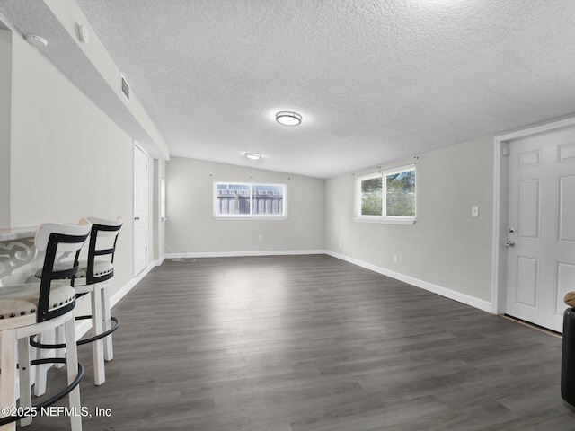 unfurnished living room featuring dark hardwood / wood-style floors, lofted ceiling, and a textured ceiling