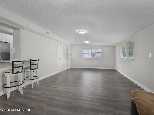 unfurnished living room with dark hardwood / wood-style floors and a textured ceiling