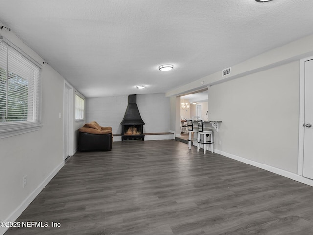 unfurnished room with a textured ceiling, a wood stove, a chandelier, and dark hardwood / wood-style floors