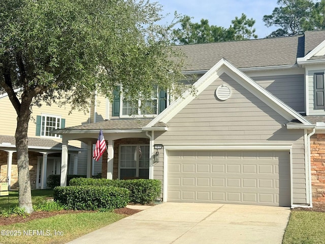 view of front of home featuring an attached garage, stone siding, driveway, and a shingled roof