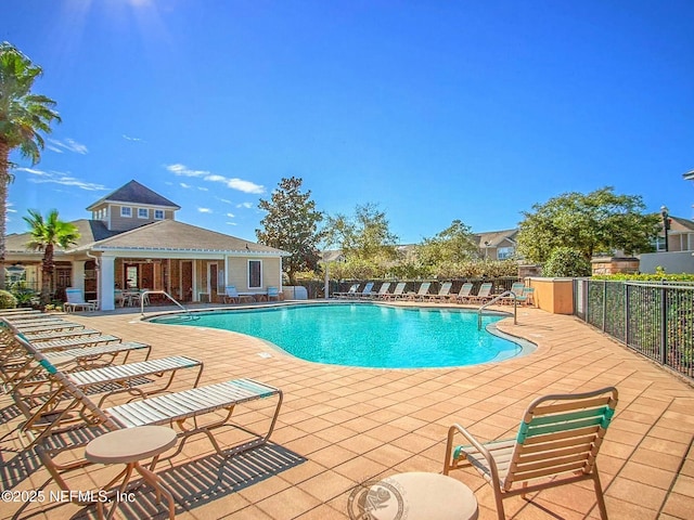 community pool with an outbuilding, a patio, and fence