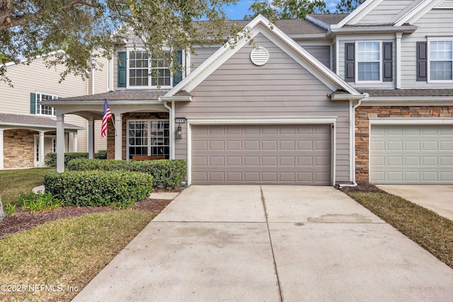 townhome / multi-family property featuring stone siding and concrete driveway