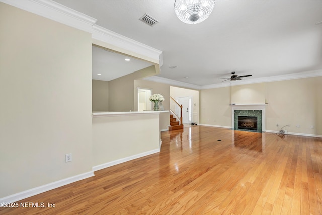 unfurnished living room featuring light wood finished floors, visible vents, baseboards, a tiled fireplace, and ornamental molding