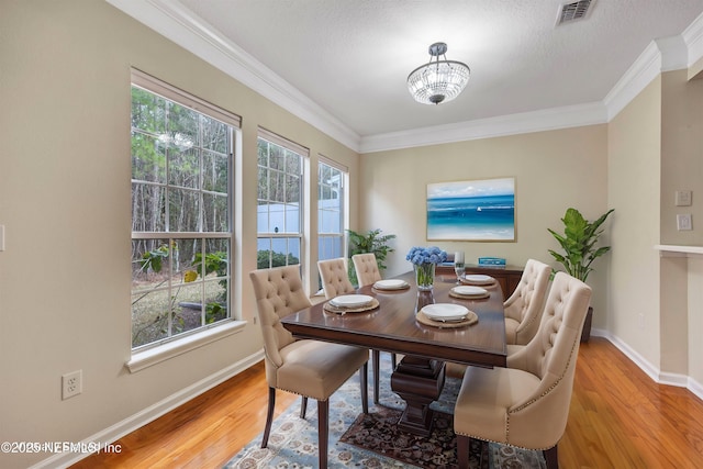 dining room with visible vents, ornamental molding, plenty of natural light, and wood finished floors