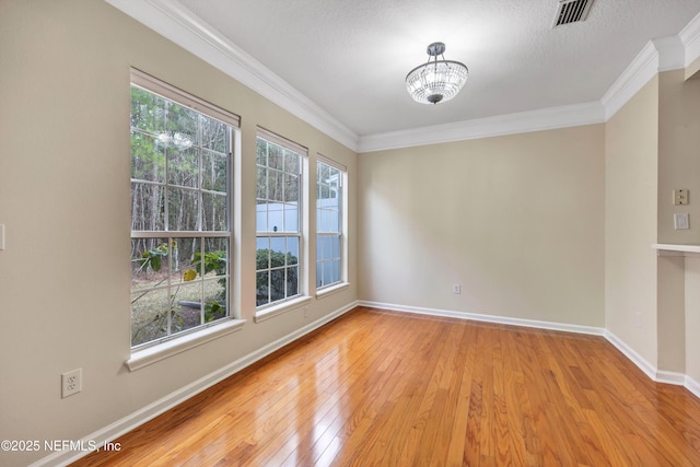 empty room with crown molding, light wood-style floors, visible vents, and a healthy amount of sunlight