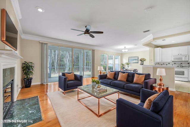 living room featuring visible vents, crown molding, baseboards, light wood-style flooring, and a tile fireplace