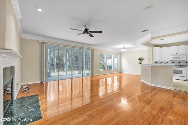 unfurnished living room with baseboards, visible vents, ornamental molding, a tile fireplace, and light wood-type flooring