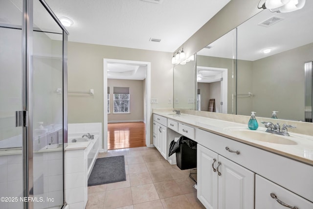 full bath featuring tile patterned flooring, visible vents, double vanity, a bath, and a sink