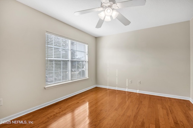 unfurnished room with a ceiling fan, wood finished floors, and baseboards