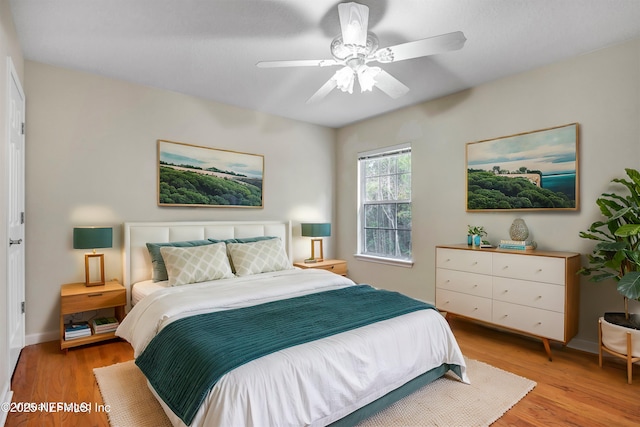 bedroom featuring light wood-style flooring, a ceiling fan, and baseboards