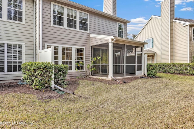 rear view of property with a lawn, a sunroom, and a chimney