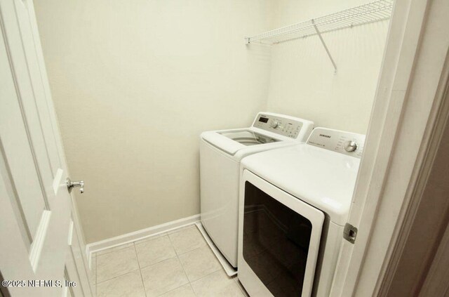 washroom featuring laundry area, light tile patterned floors, baseboards, and washer and clothes dryer