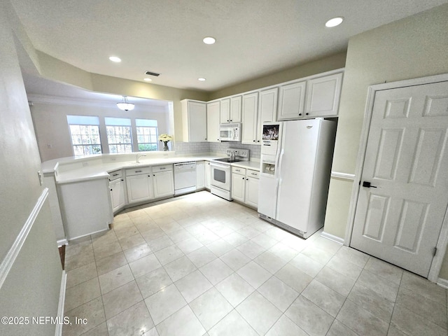 kitchen with white appliances, white cabinets, light countertops, and tasteful backsplash