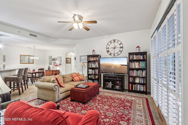 living room with ceiling fan with notable chandelier and a textured ceiling