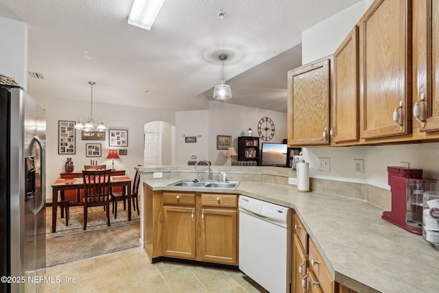 kitchen featuring dishwasher, sink, stainless steel fridge, and kitchen peninsula