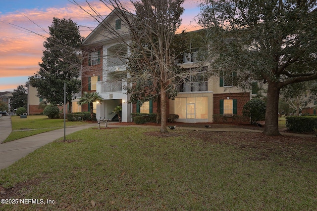 view of front of property featuring a balcony and a lawn