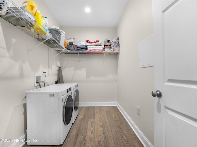 clothes washing area with hardwood / wood-style floors and washing machine and dryer