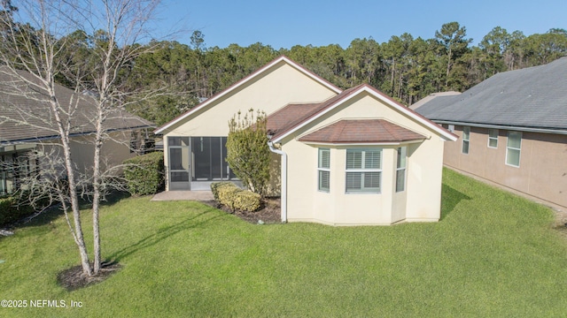 rear view of property featuring a sunroom and a lawn