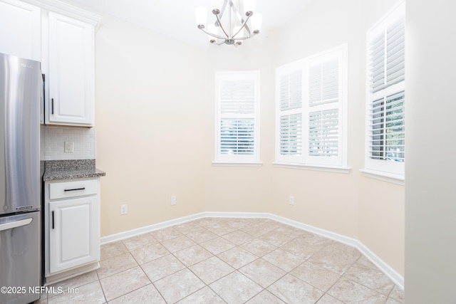 unfurnished dining area featuring a notable chandelier, a healthy amount of sunlight, and light tile patterned floors