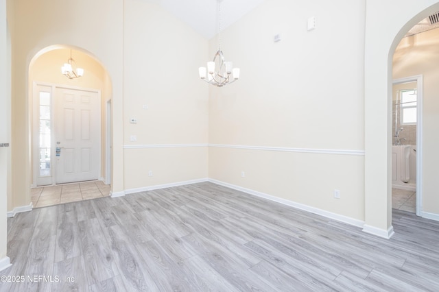 entryway featuring high vaulted ceiling, a chandelier, and light hardwood / wood-style floors