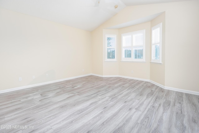 spare room with vaulted ceiling and light wood-type flooring