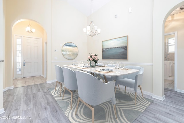 dining space featuring high vaulted ceiling, a notable chandelier, and light wood-type flooring