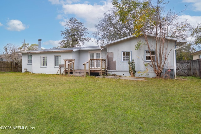 rear view of property featuring a wooden deck and a lawn