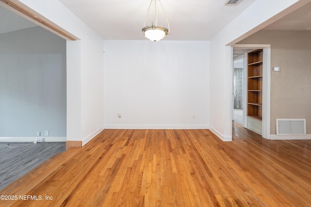 unfurnished room featuring built in features and light hardwood / wood-style floors