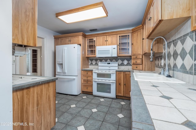 kitchen featuring tile countertops, sink, backsplash, and white appliances