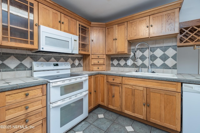 kitchen with light tile patterned floors, backsplash, sink, and white appliances