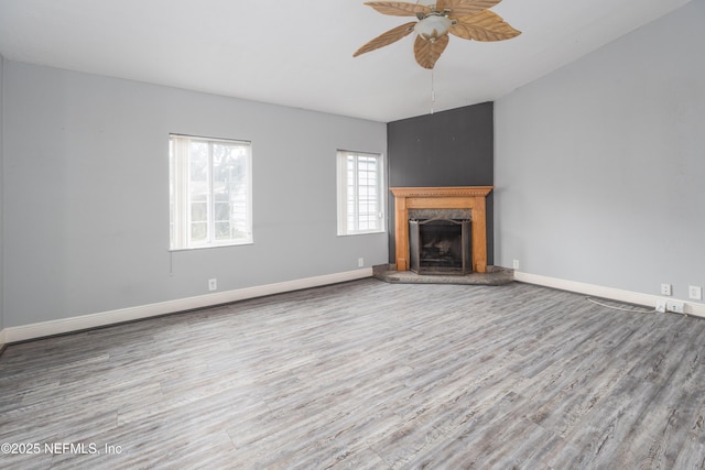 unfurnished living room featuring ceiling fan, wood-type flooring, and a premium fireplace