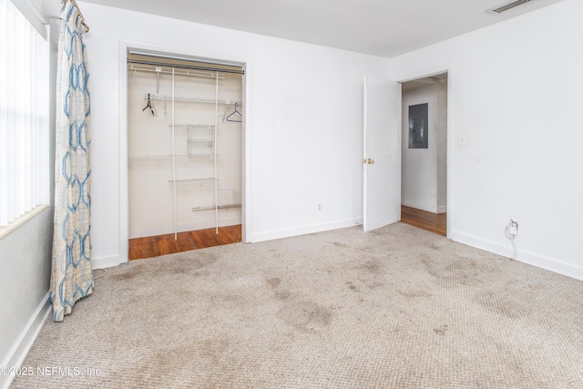 unfurnished bedroom with a closet, electric panel, and carpet floors