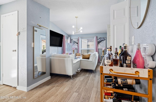 living room with hardwood / wood-style floors, lofted ceiling, and a notable chandelier