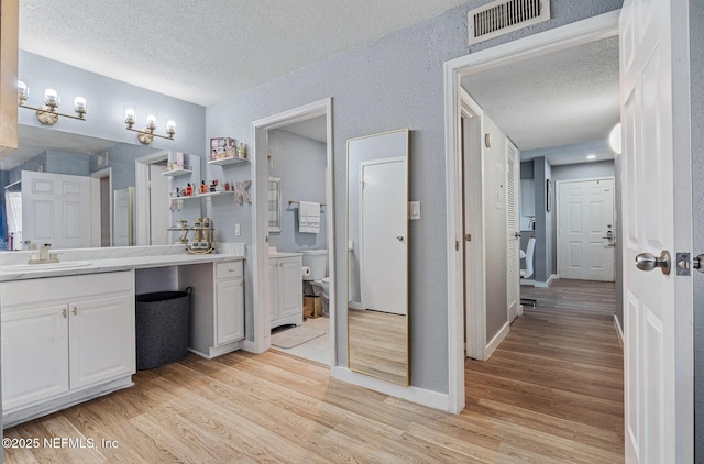 bathroom featuring vanity, hardwood / wood-style floors, a textured ceiling, and toilet