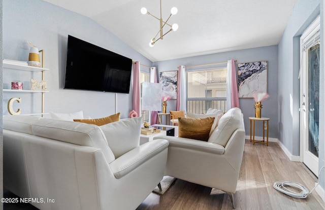 living room with light hardwood / wood-style flooring, lofted ceiling, and a notable chandelier