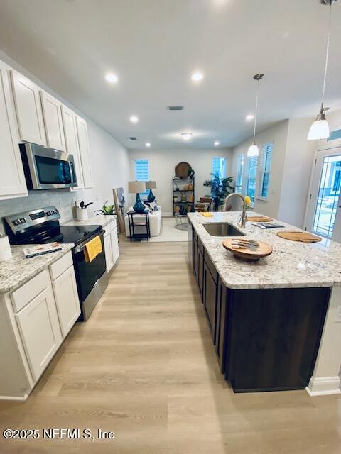 kitchen featuring white cabinetry, pendant lighting, stainless steel appliances, and sink