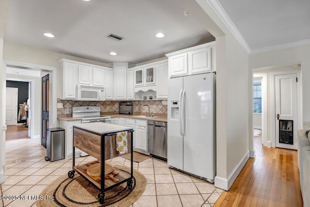 kitchen featuring decorative backsplash, crown molding, white cabinets, and white appliances