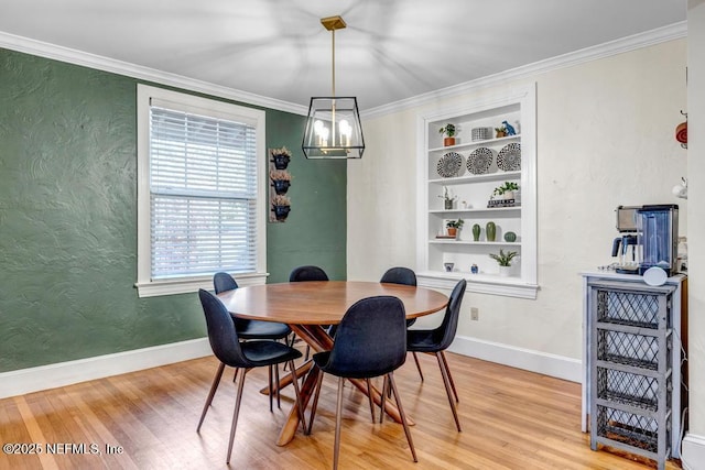 dining space featuring a notable chandelier, light hardwood / wood-style floors, built in features, and ornamental molding