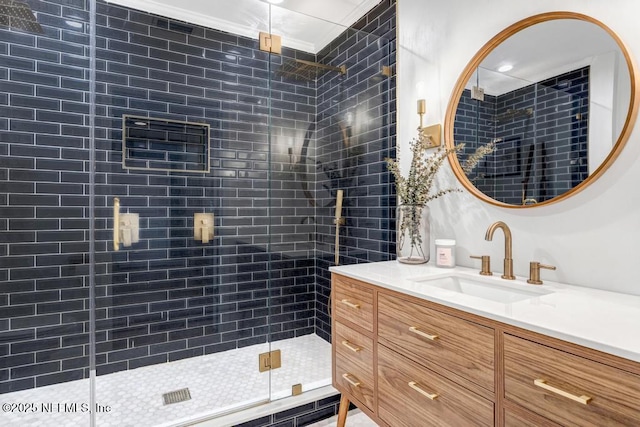 bathroom featuring vanity, a shower with shower door, and ornamental molding